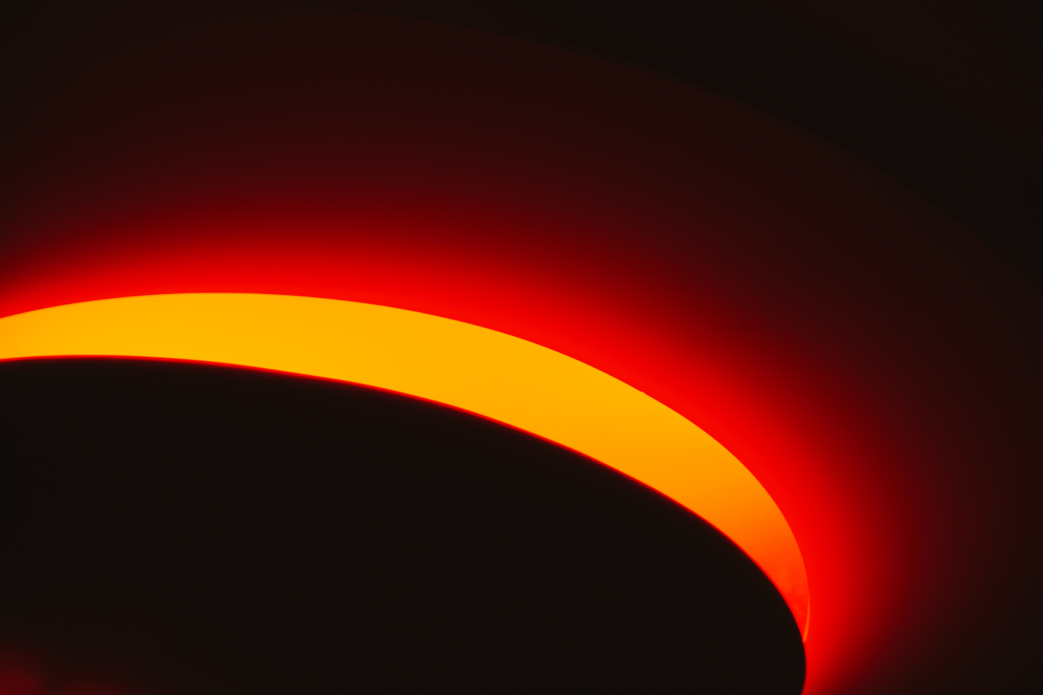 abstracte afbeelding waarin een zwarte cirkel omgeven wordt door een gele en rode gloed